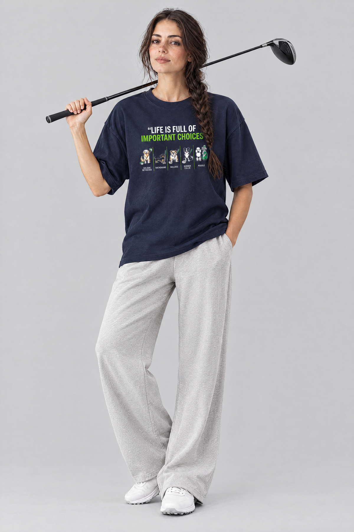 Woman wearing the Full of Choices Dog Golf Tee in navy with light grey trousers and a driver on her shoulder. Color: Navy