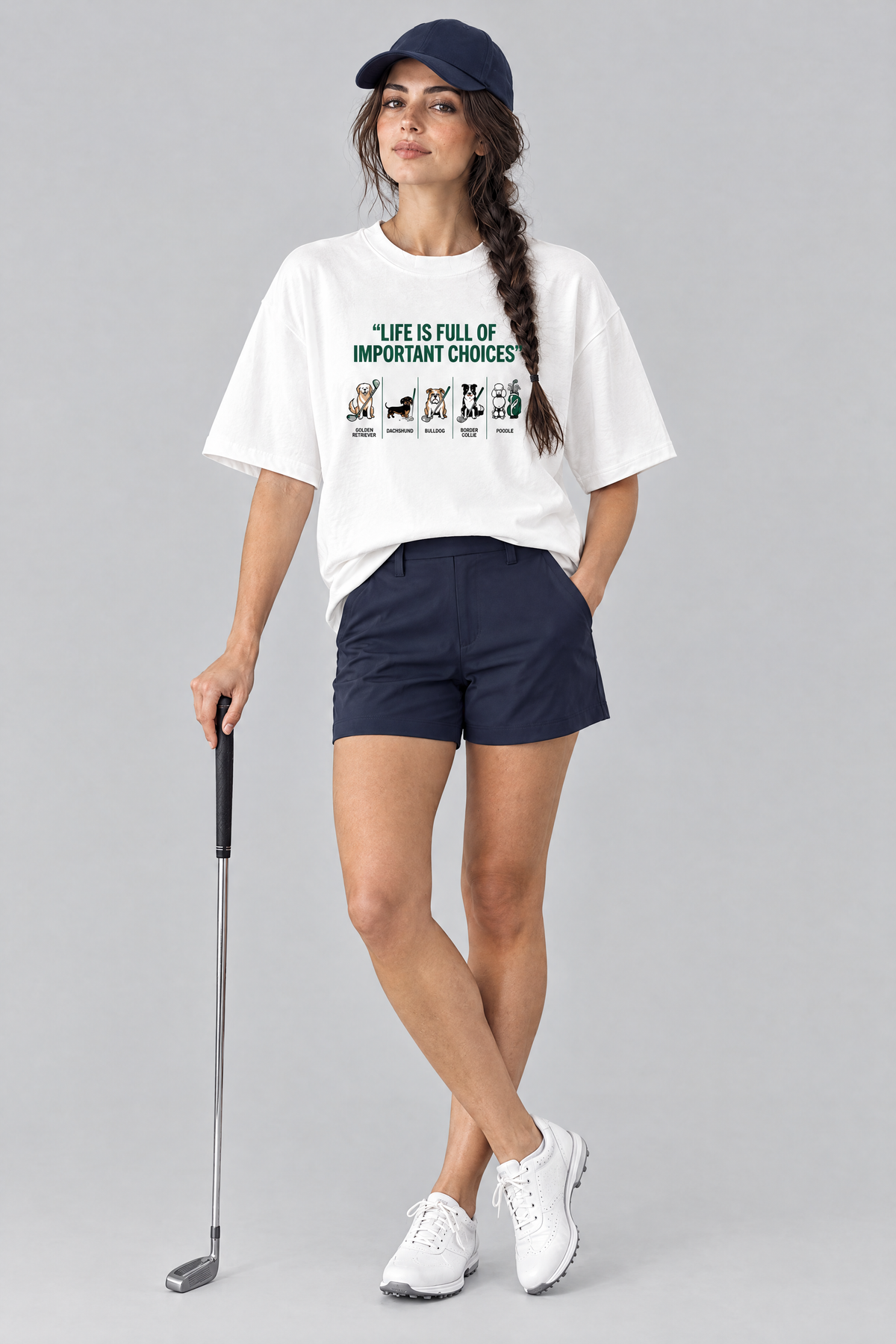 Woman wearing the Full of Choices Dog Golf Tee in white with navy golf shorts and a navy cap. Color: White
