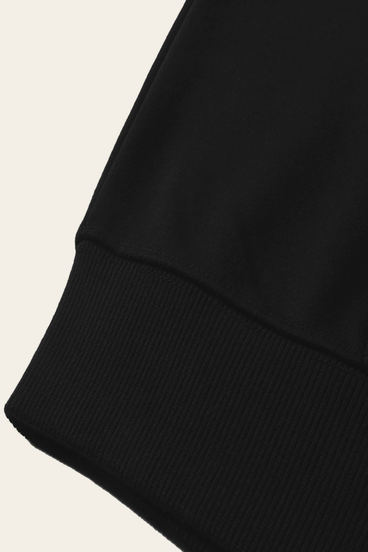 Detail of the ribbed cuff of the black golf hoodie. Color: Black