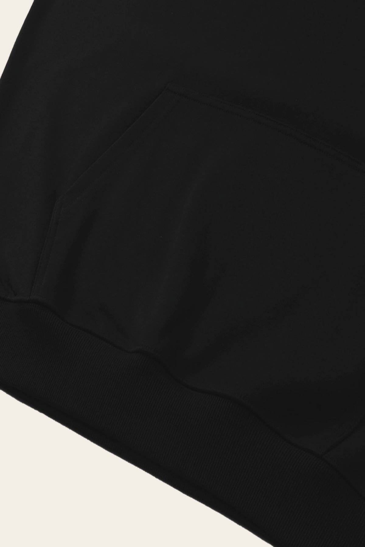 Detail of the kangaroo pocket and ribbed hem of the black golf hoodie. Color: Black