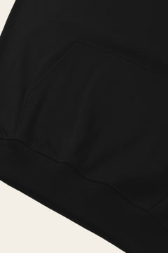 Detail of the kangaroo pocket and ribbed hem of the black golf hoodie. Color: Black