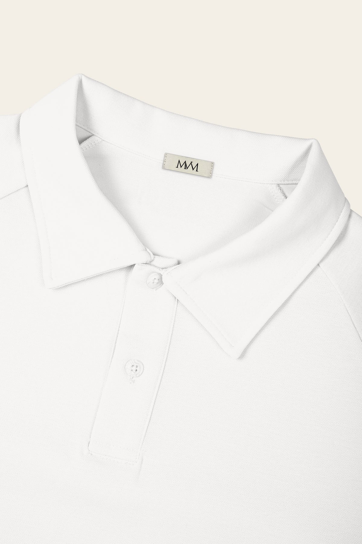 Close-up of the collar and two-button placket of the white golf polo with the MVM woven neck label. Color: White