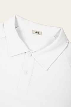 Close-up of the collar and two-button placket of the white golf polo with the MVM woven neck label. Color: White