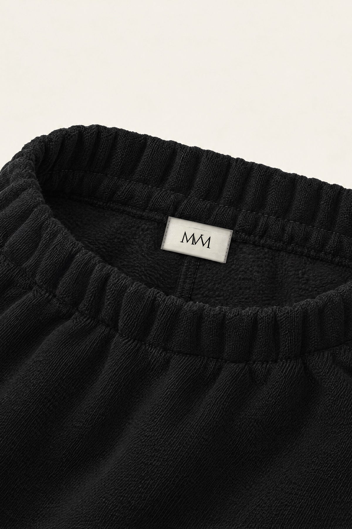 Inside of the back waistband of the black golf sweatpants with the MVM woven label. Color: Black