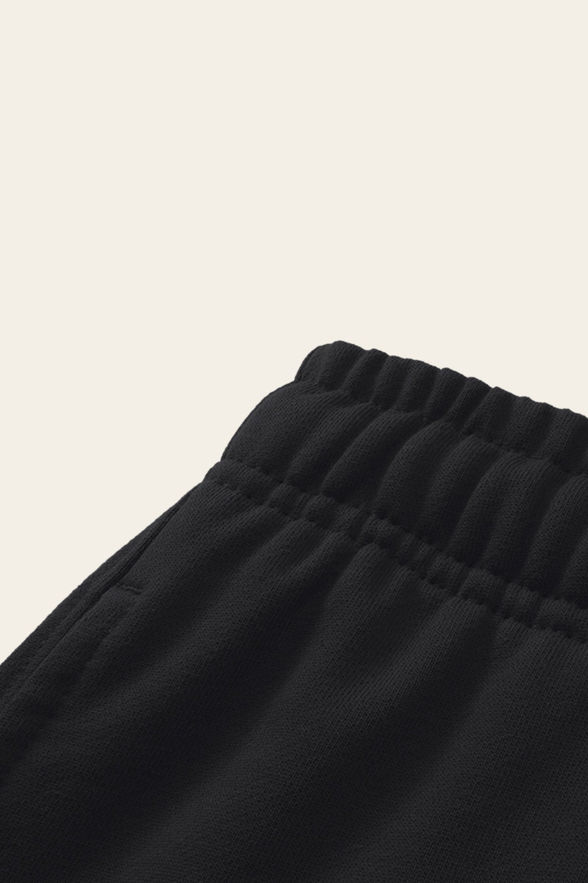 Detail of the elastic waistband and side pocket of the black golf sweatpants. Color: Black