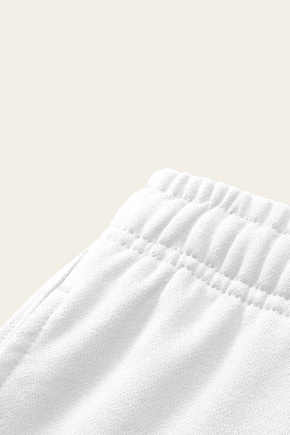 Detail of the elastic waistband and side pocket of the white golf sweatpants. Color: White