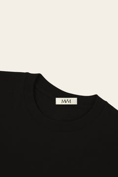 Close-up of the ribbed crew neck of the black golf t-shirt with the MVM woven neck label. Color: Black
