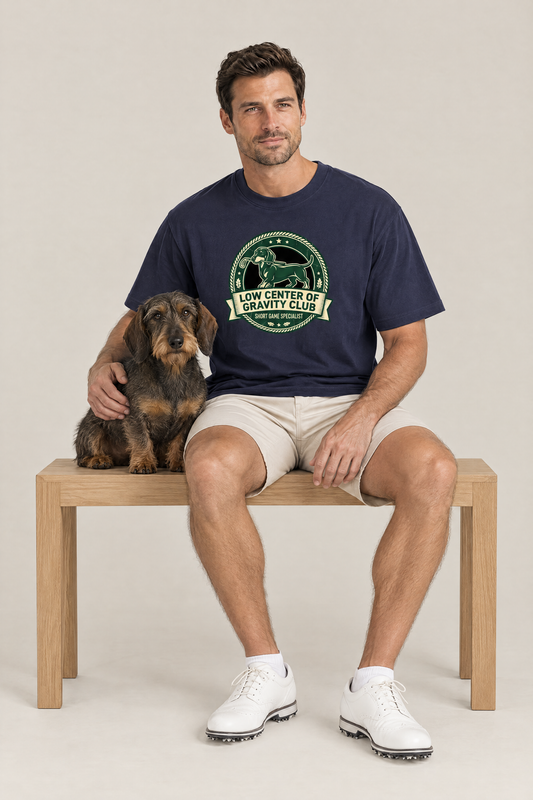 Man sitting on a bench with a wire-haired dachshund in the navy Low Center of Gravity Club Dachshund Golf Tee. Color: Navy