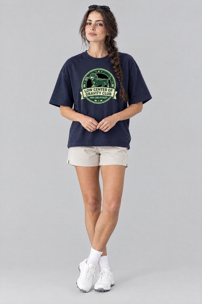 Woman wearing the Low Center of Gravity Club Dachshund Golf Tee in navy with stone golf shorts and sunglasses on her head. Color: Navy