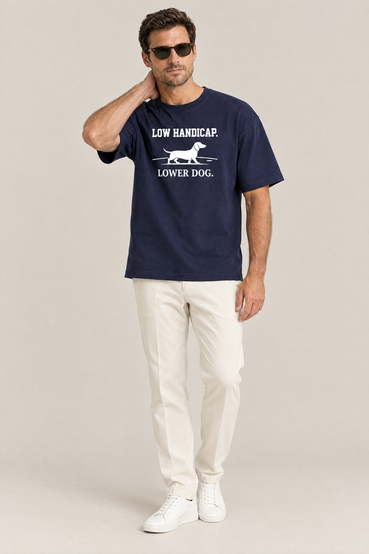 Man wearing the Low Handicap Dachshund Golf Tee in navy with off-white trousers and sunglasses. Color: Navy