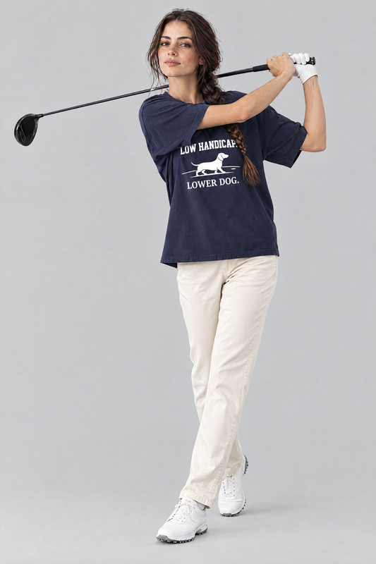Woman finishing a golf swing with a driver in the navy Low Handicap Dachshund Golf Tee and cream chinos. Color: Navy
