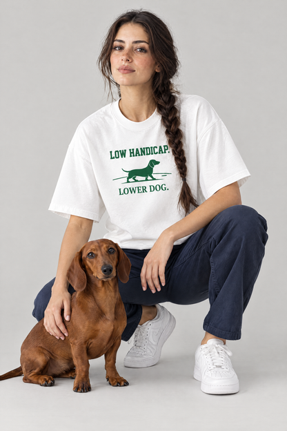 Woman crouching next to a red dachshund in the white Low Handicap Dachshund Golf Tee. Color: White