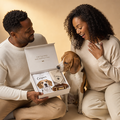 Man and woman with a dog looking at a gift box containing personalized pet items.