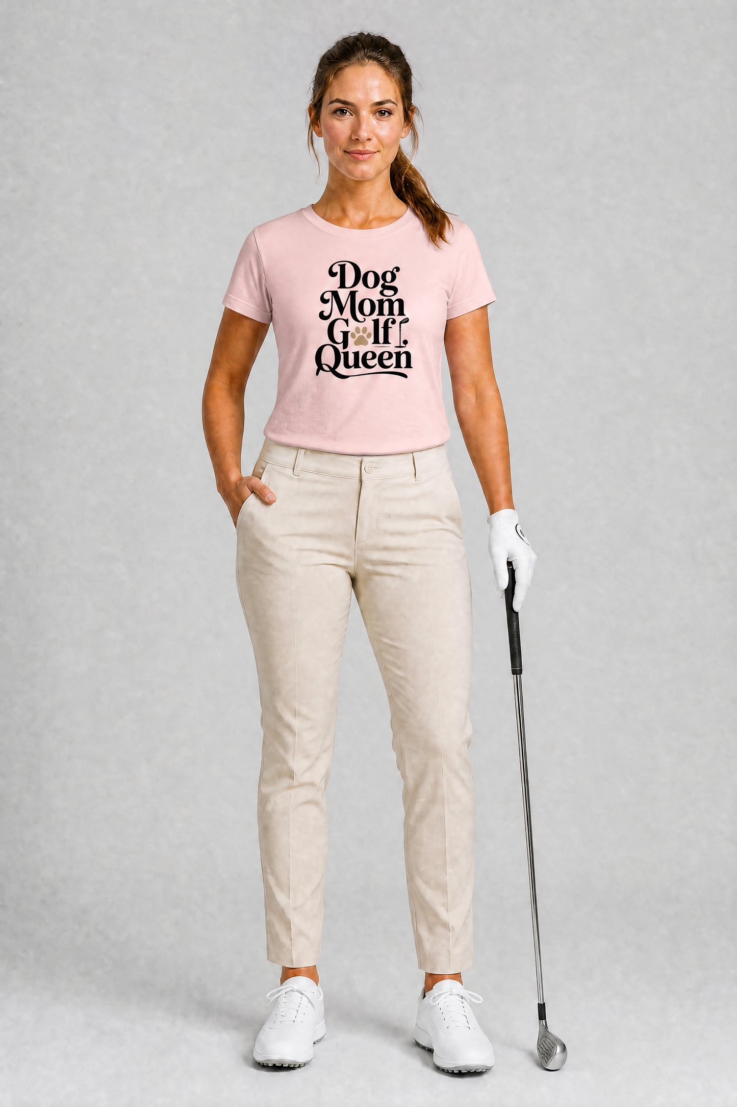 Woman wearing a pink t-shirt with 'Dog Mom Golf Queen' text, holding a golf club on a gray background