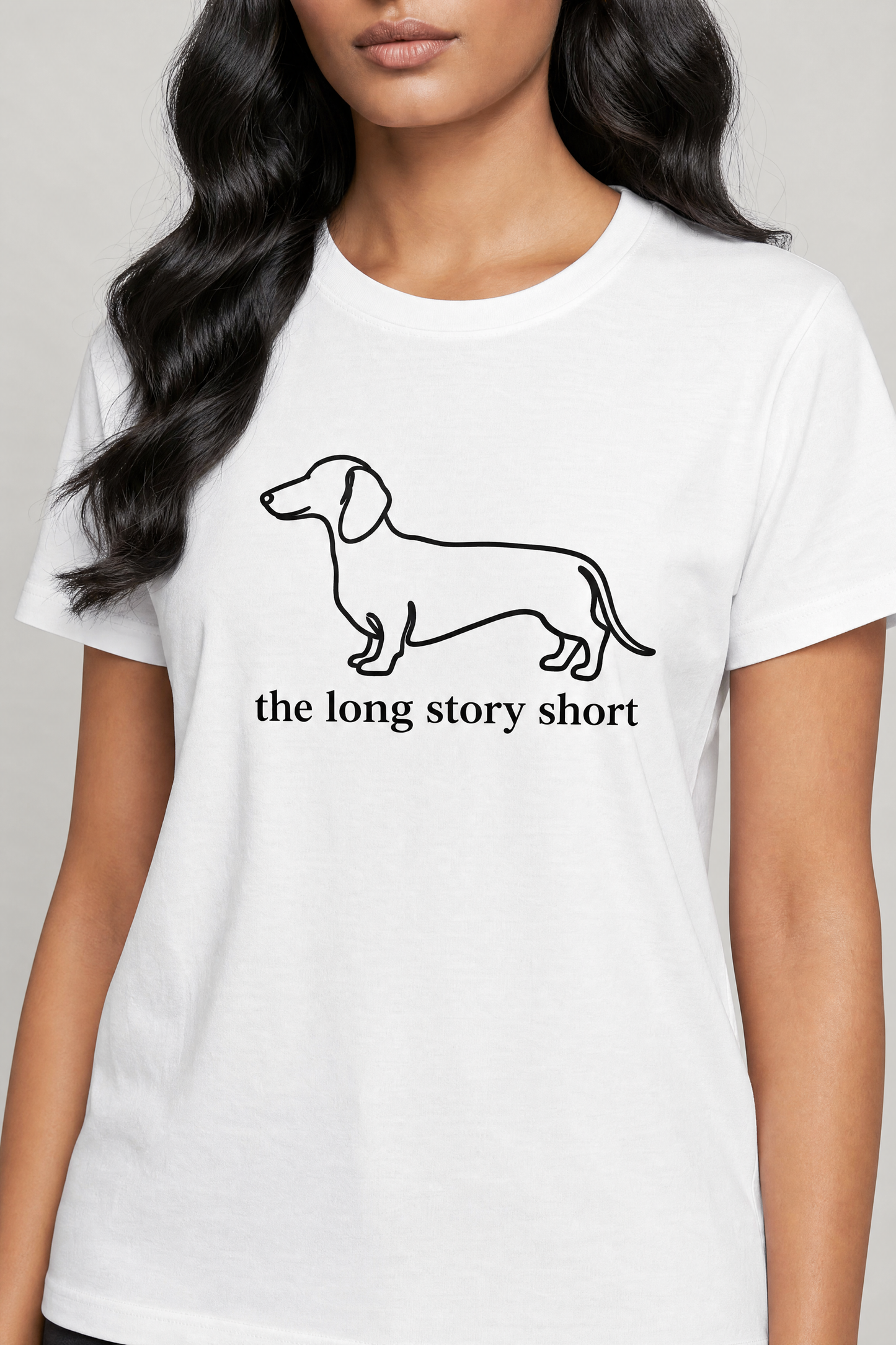 White t-shirt with dachshund graphic and text worn by a person on a plain background