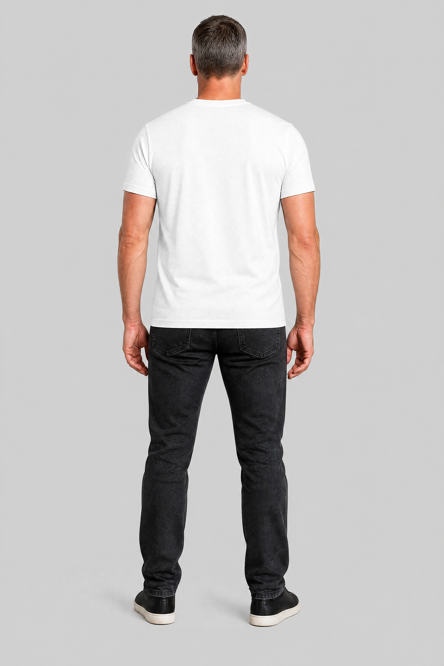 Man wearing a white t-shirt and black jeans on a gray background