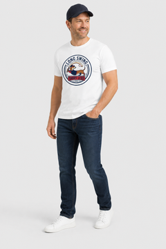 Man wearing a white t-shirt with a logo and dark jeans on a light gray background