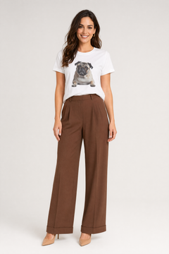 Woman wearing a white t-shirt with a pug graphic and brown pants on a white background