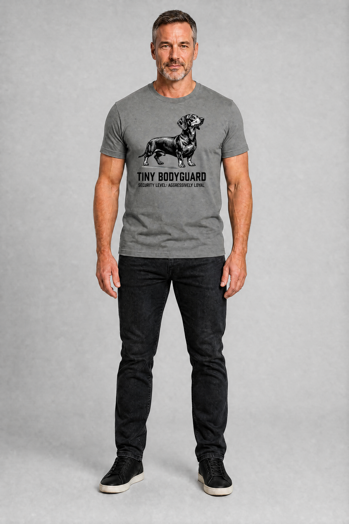 Man wearing a gray t-shirt with a graphic design on a plain background