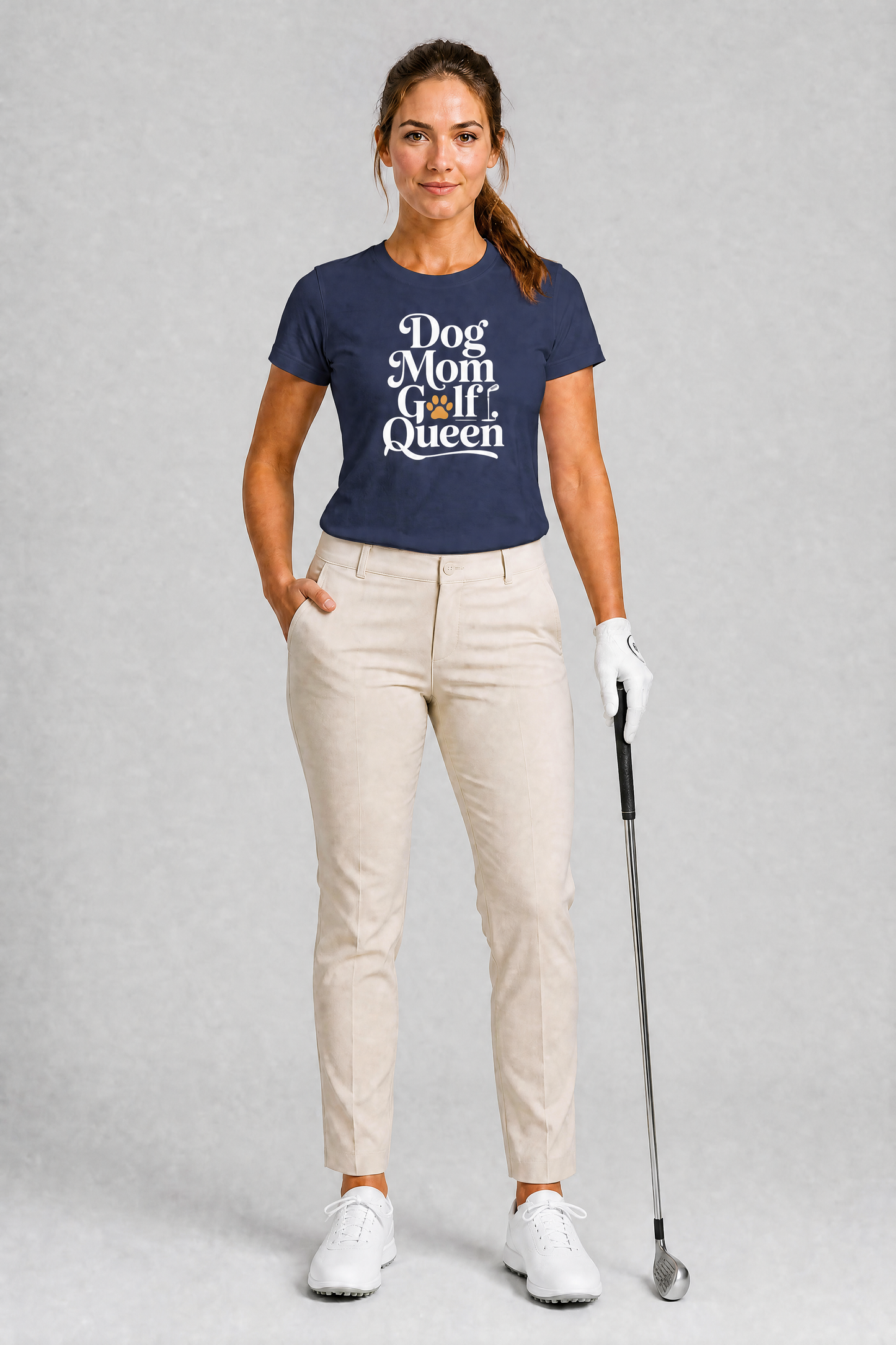 Woman wearing a navy t-shirt with 'Dog Mom Golf Queen' text, holding a golf club on a gray background