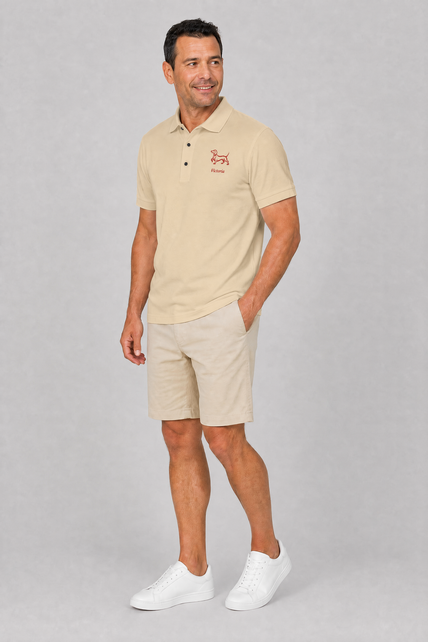White pique dachshund polo shirt with embroidered red doxie and name, flat lay detail