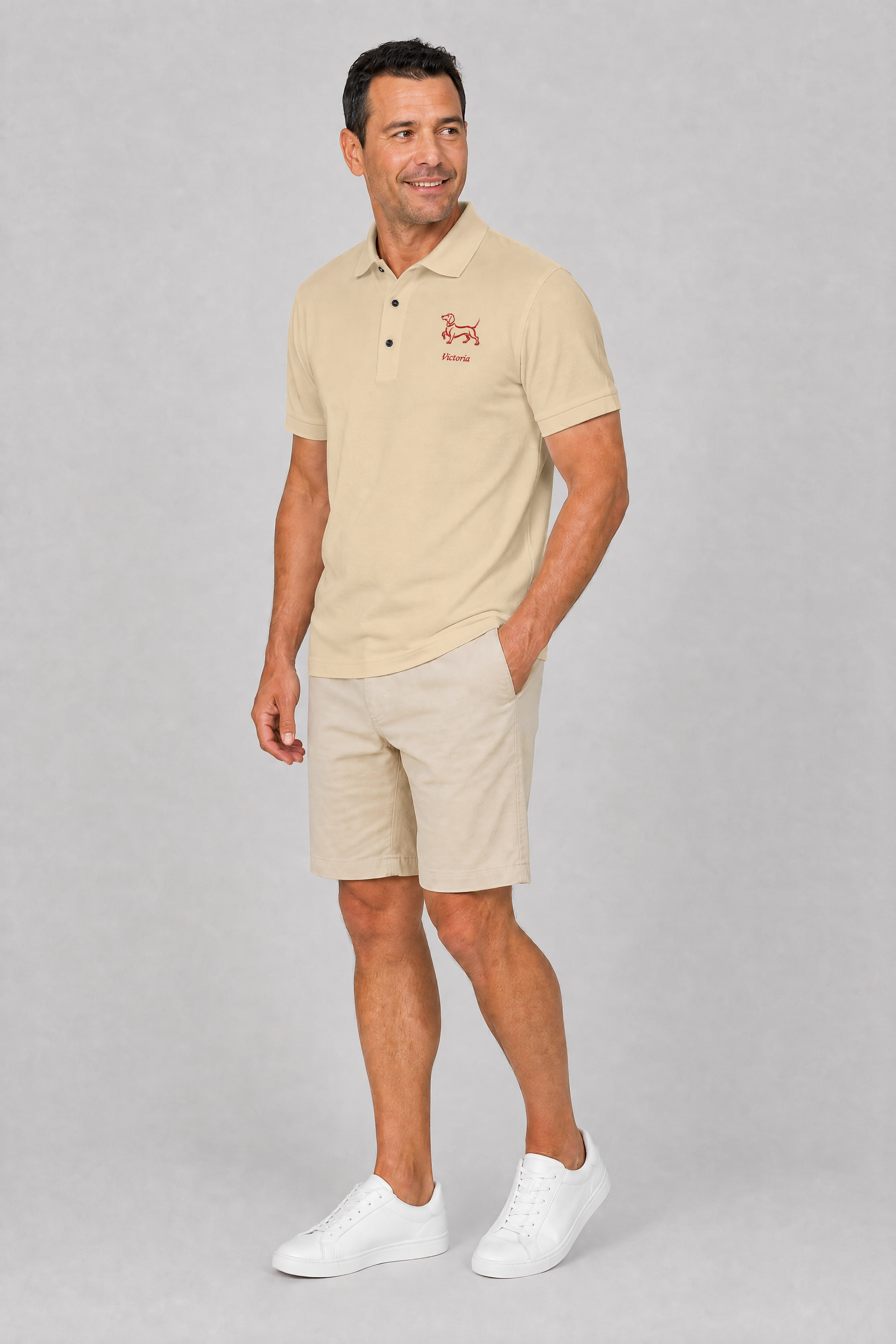 White pique dachshund polo shirt with embroidered red doxie and name, flat lay detail