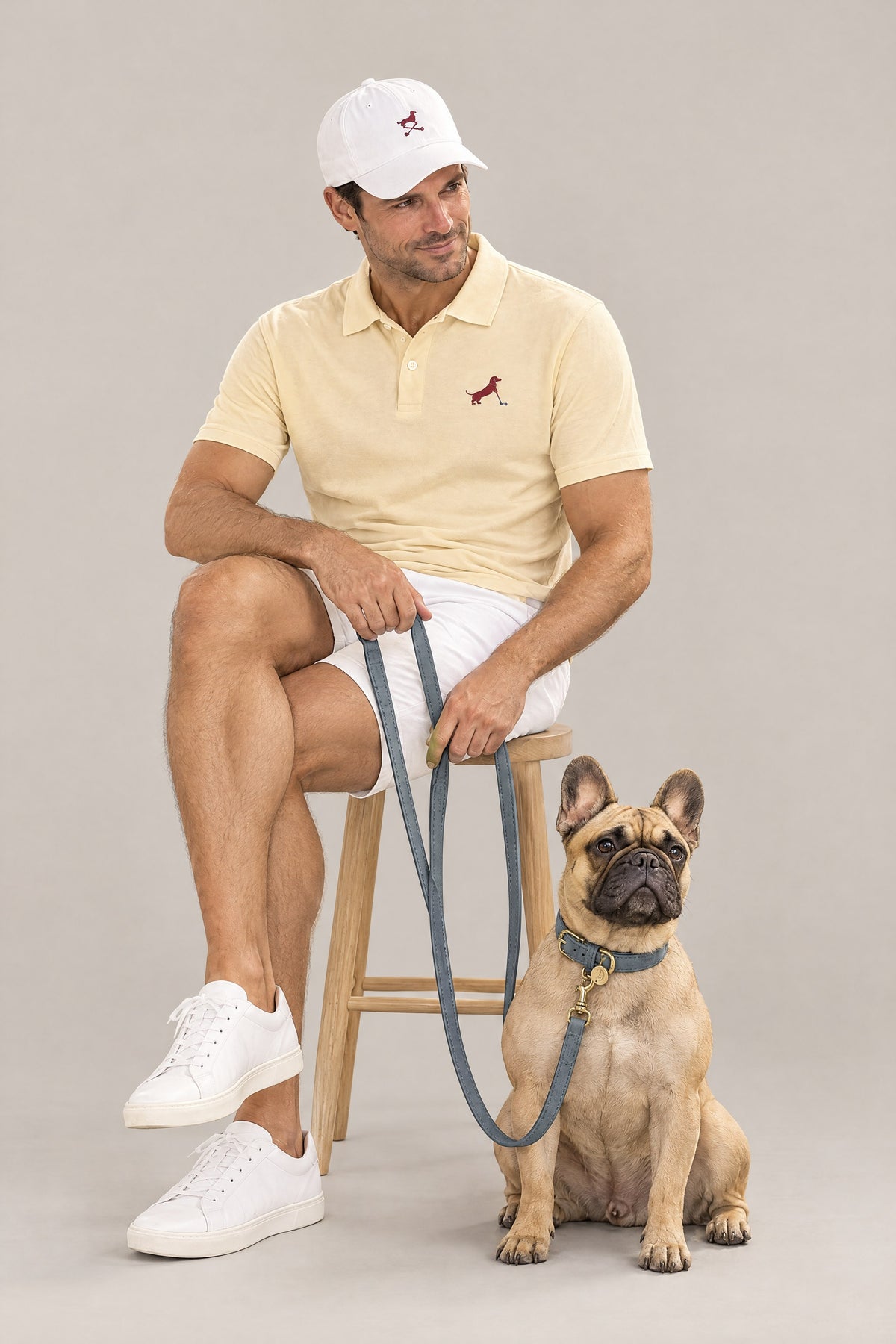 Man in the butter yellow Putting dachshund golf polo seated with a French Bulldog on the dove grey Cloud 7 Tiergarten leash