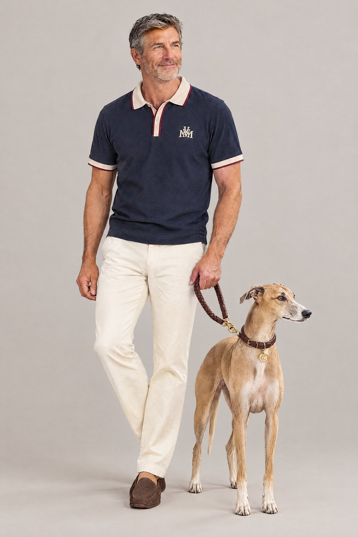 Man in the navy Club Crest color block polo with a whippet wearing the hazel Cloud 7 Ravello collar and braided leash