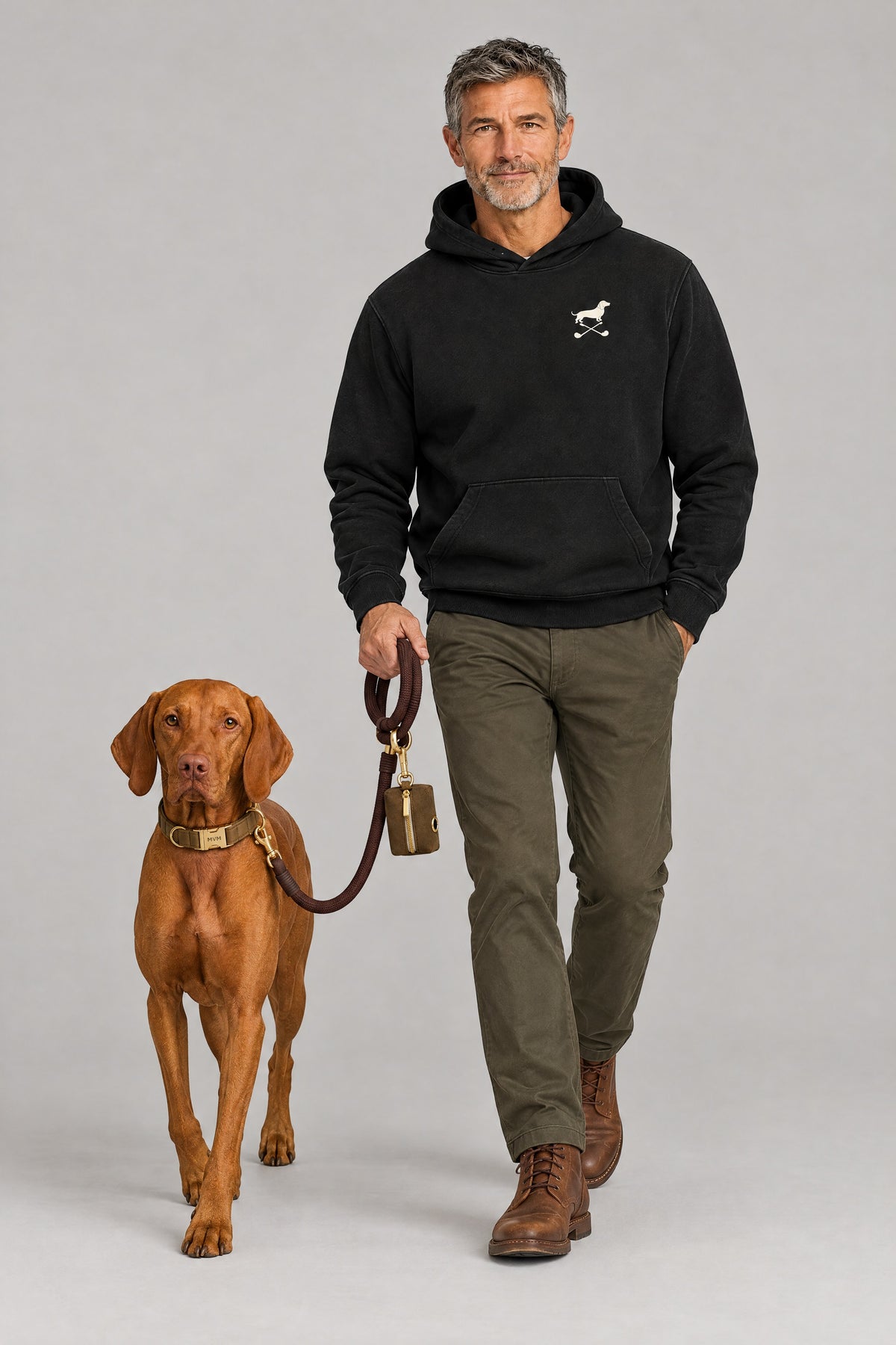 Man in the black Club and Swing dachshund golf hoodie walking a Vizsla on the chocolate MVM Evergreen set