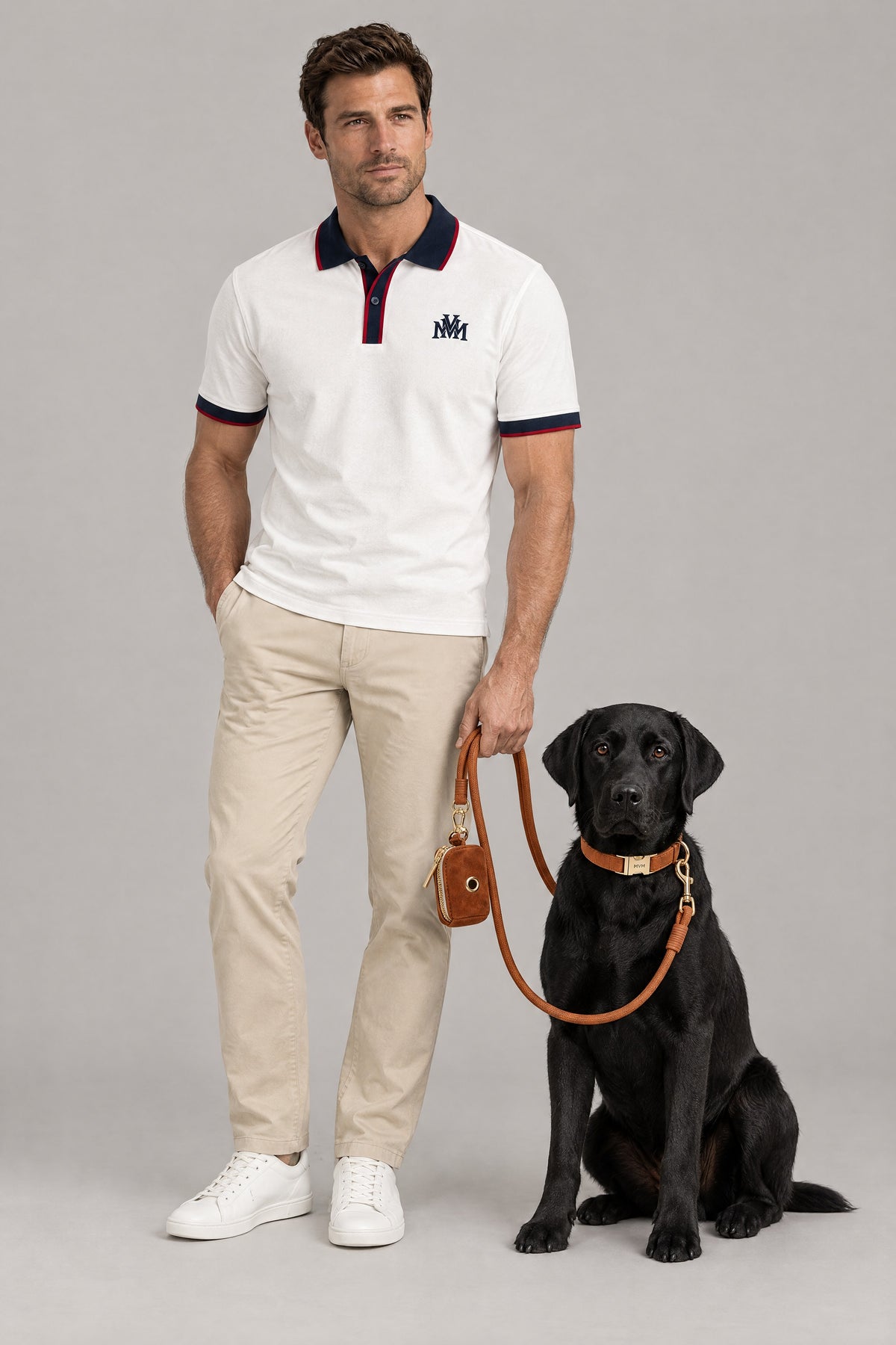Man in the white navy Club Crest color block polo with a black Labrador wearing the camel MVM Evergreen set