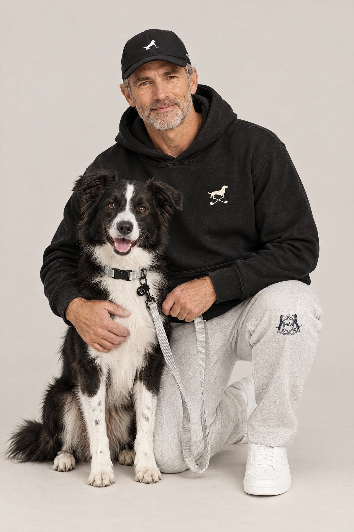 Man in the black Club & Swing Dachshund golf hoodie hugging a rescue dog wearing the Cloud 7 RESC7UE Silver collar and leash