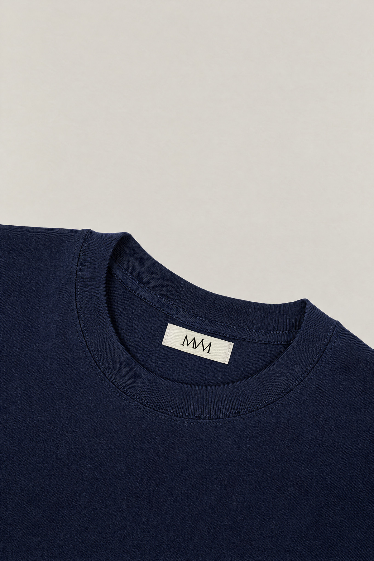 Ribbed crew neck of the navy heavyweight cotton tee with the MVM woven neck label, close-up. Color: Navy