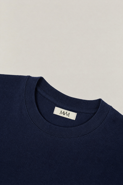 Ribbed crew neck of the navy heavyweight cotton tee with the MVM woven neck label, close-up. Color: Navy