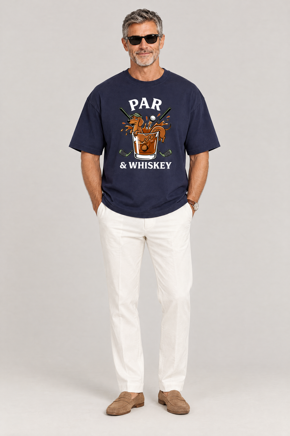 Man wearing the Par & Whiskey Dachshund Golf Tee in navy with white trousers and sunglasses. Color: Navy