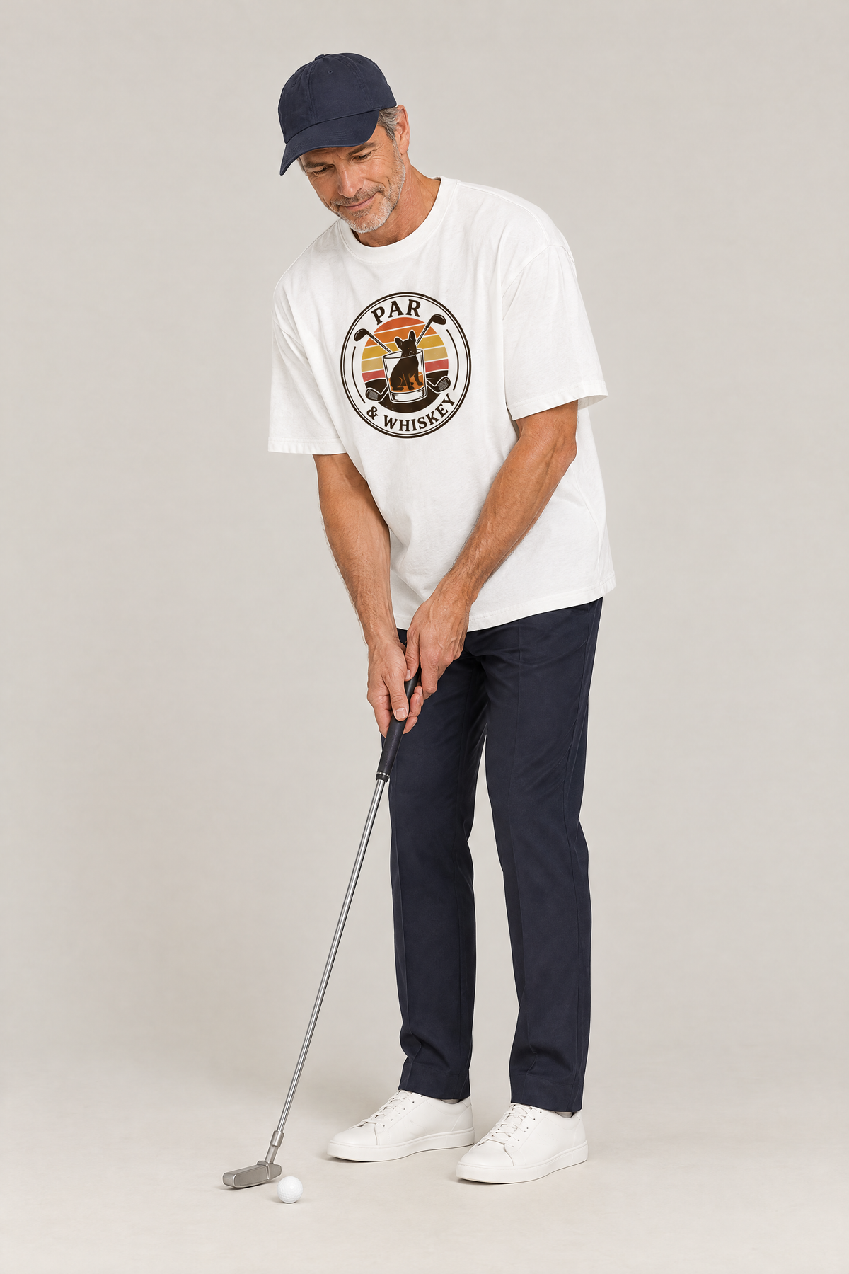 Man lining up a putt in the white Par & Whiskey French Bulldog Badge Golf Tee. Color: White