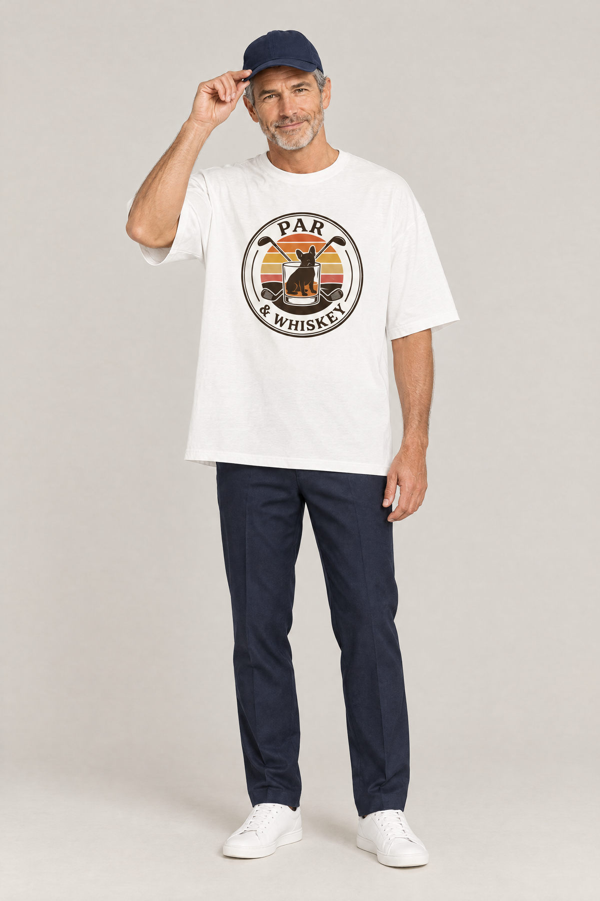 Man wearing the Par & Whiskey French Bulldog Badge Golf Tee in white with navy trousers and a navy cap. Color: White