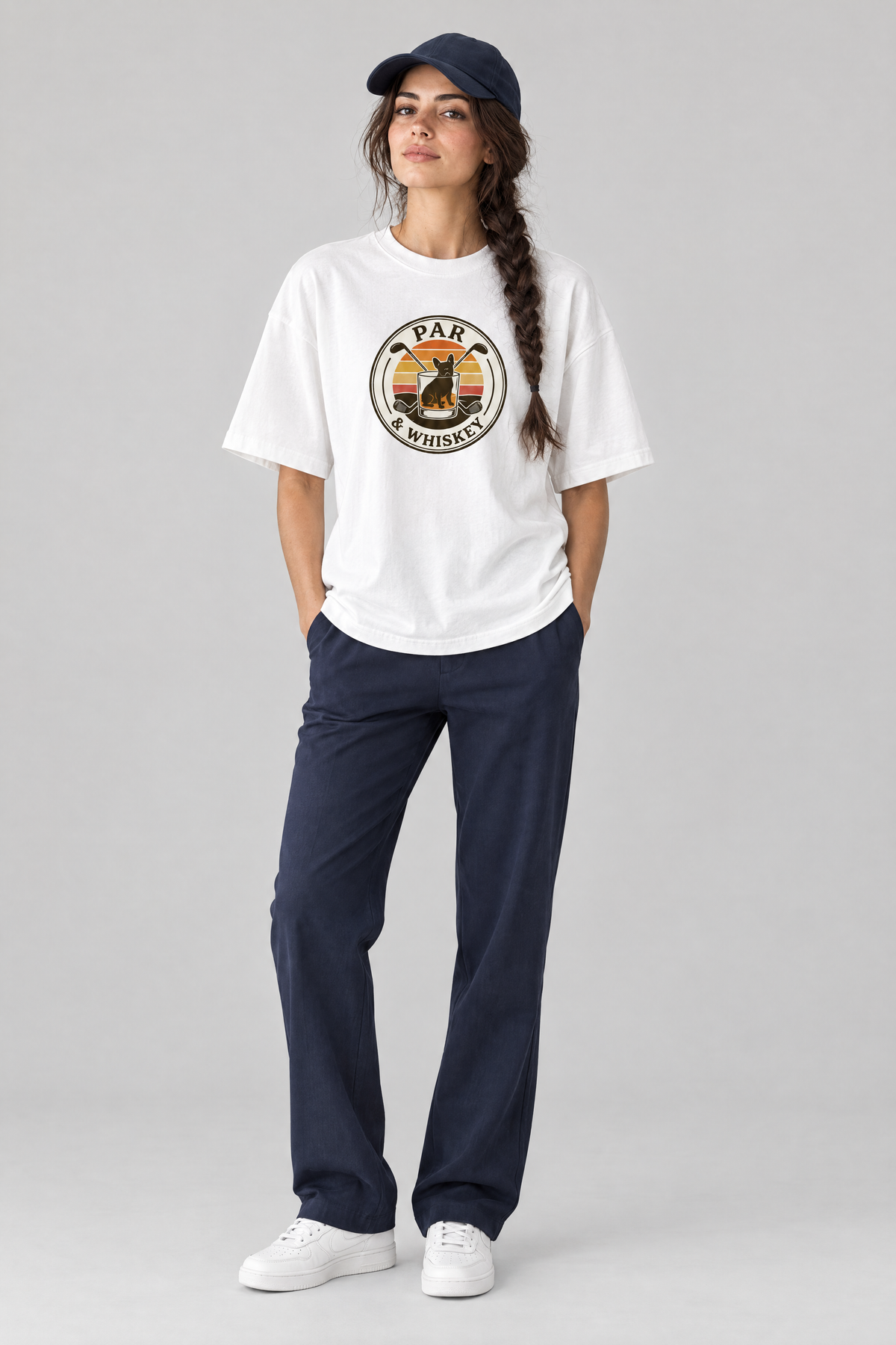 Woman wearing the Par & Whiskey French Bulldog Badge Golf Tee in white with navy trousers and a navy cap. Color: White