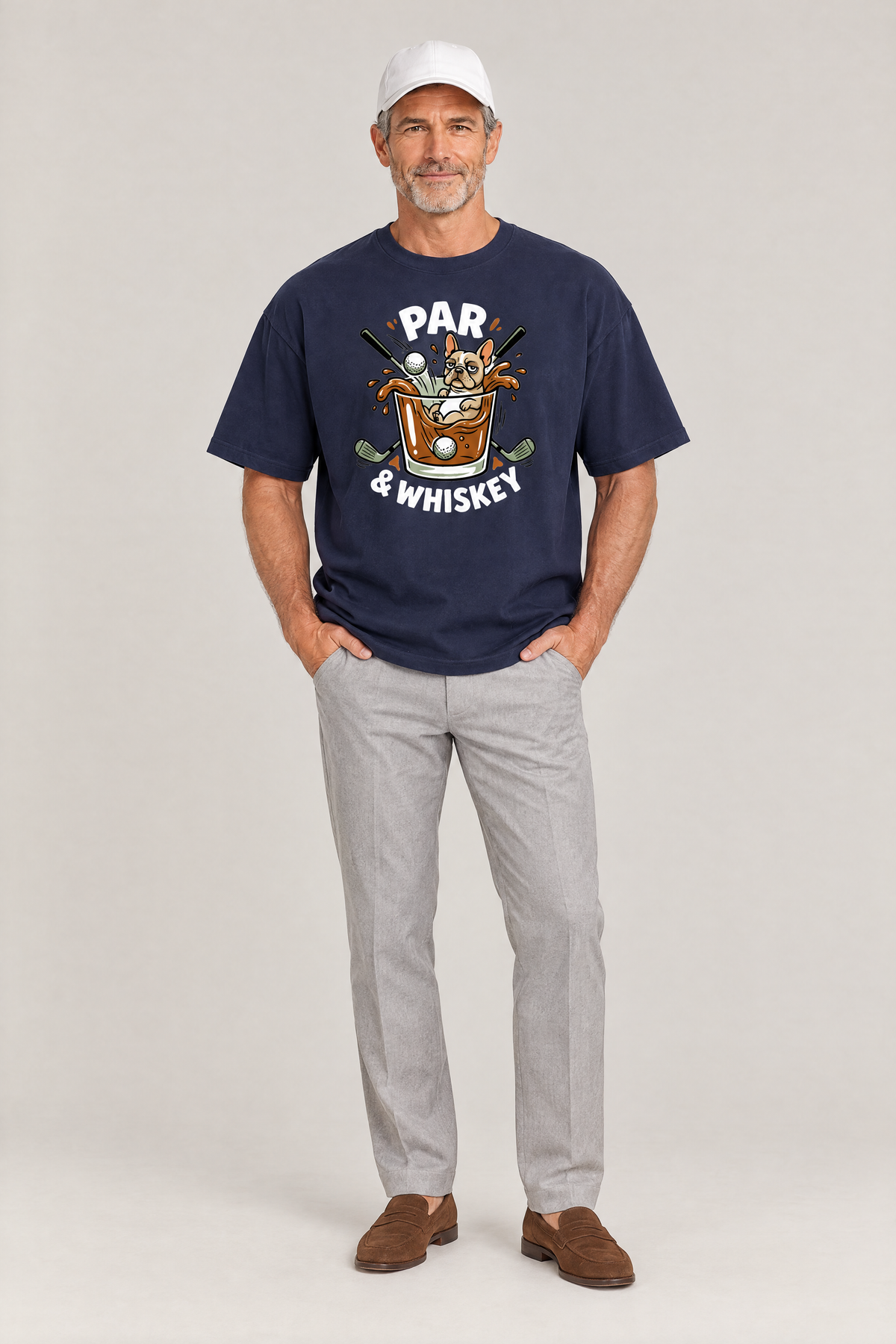 Man wearing the Par & Whiskey French Bulldog Splash Golf Tee in navy with grey trousers and a white cap. Color: Navy