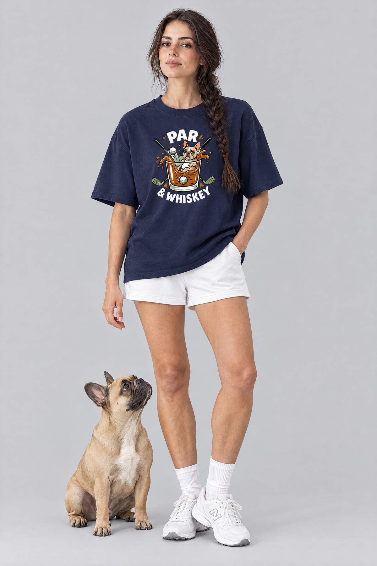 Woman wearing the Par & Whiskey French Bulldog Splash Golf Tee in navy with a French bulldog sitting at her feet. Color: Navy