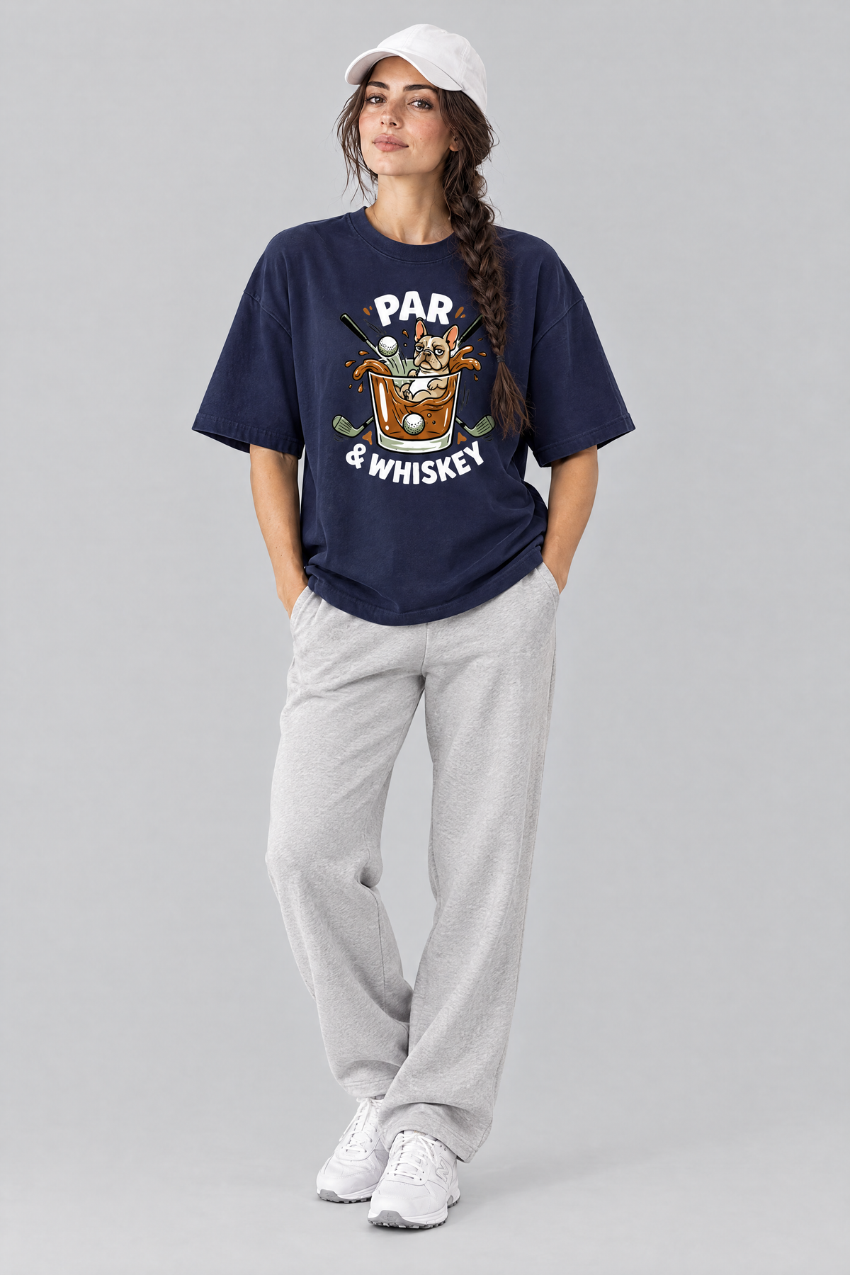 Woman wearing the Par & Whiskey French Bulldog Splash Golf Tee in navy with light grey trousers and a white cap. Color: Navy