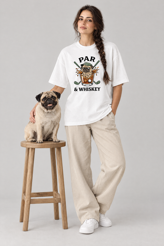 Woman wearing the Par & Whiskey Pug Golf Tee in white with a pug on a wooden stool. Color: White