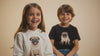 Happy children wearing dog-themed apparel with cute pug illustrations in a lifestyle studio setting.