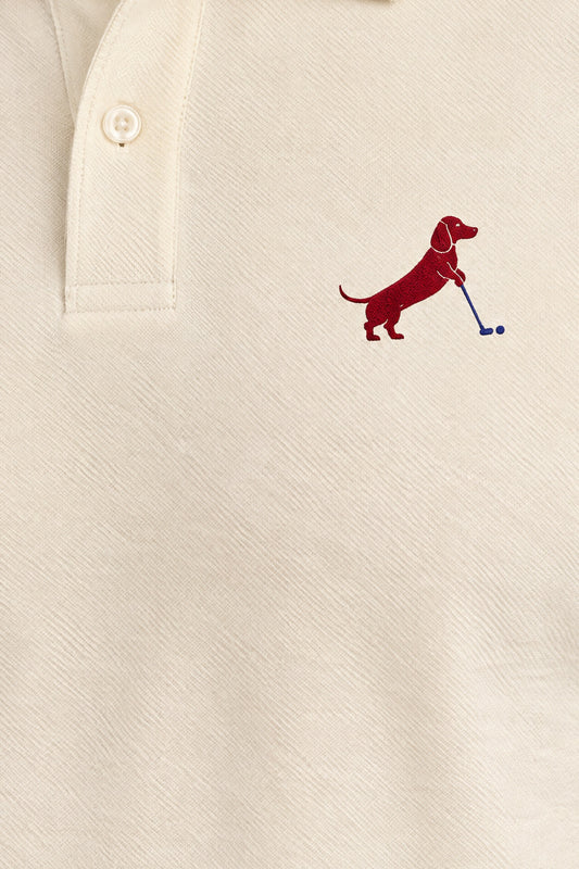Close-up of collar and chest logo on apricot Putting dachshund golf polo. Color: Apricot