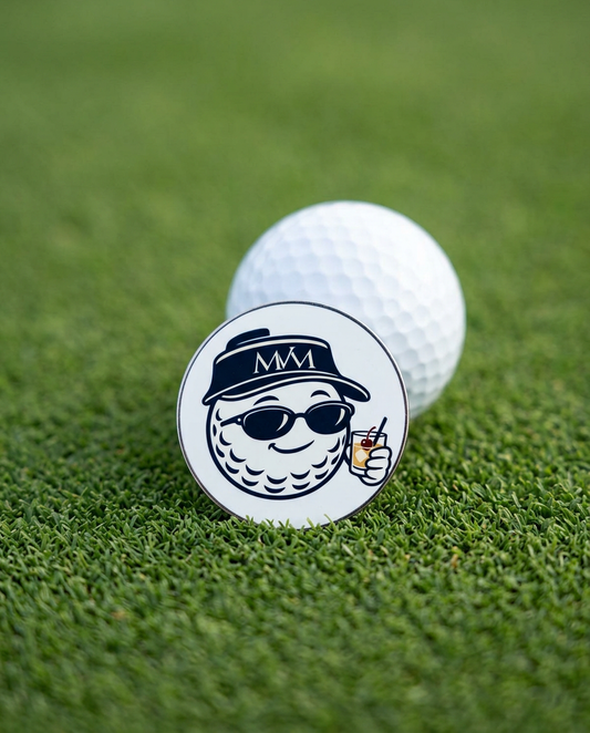 19th Hole golf ball marker in navy and cream print on a putting green next to a golf ball