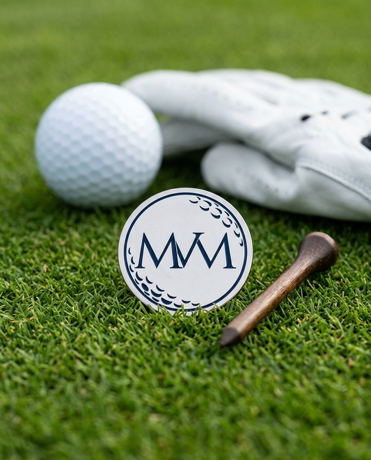 Pure Ball golf ball marker in navy and cream print on grass with a wooden tee and golf glove