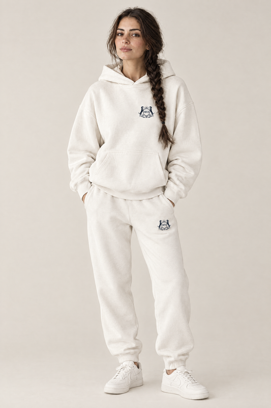 Woman in a matching white set: Club Crest hoodie and sweatpants, both with a small navy Golf & Dachshund Club crest
