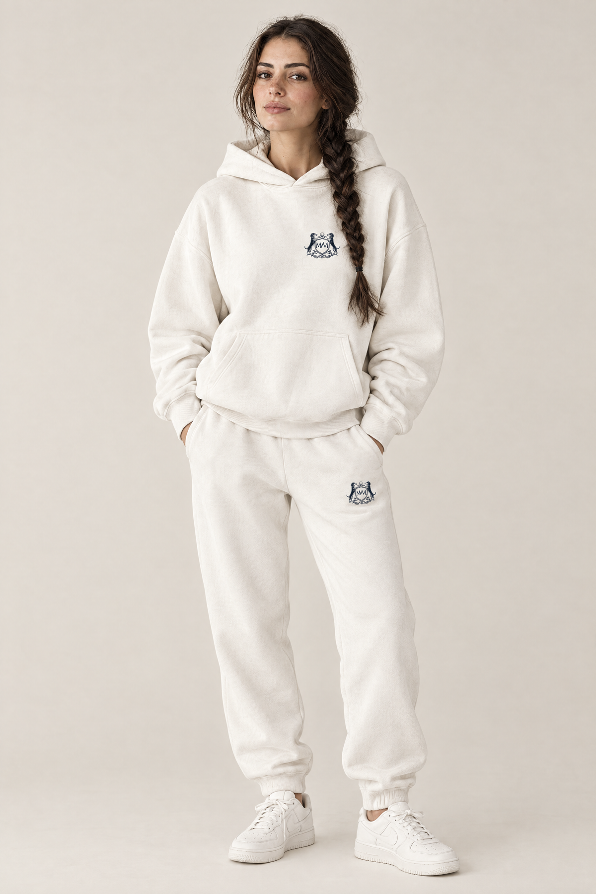 Woman in a matching white set: Club Crest hoodie and sweatpants, both with a small navy Golf & Dachshund Club crest