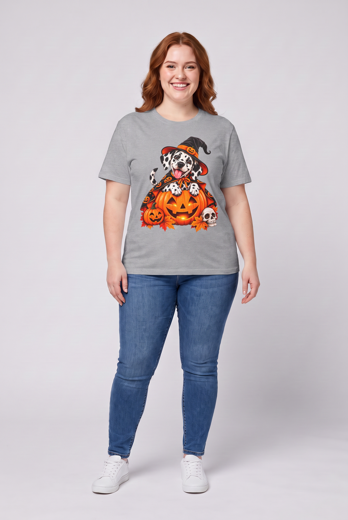 Frau trägt ein Dalmatiner Hexen Halloween T-Shirt in Sport Grey mit Dalmatiner in Hexenhut und Kürbis-Umhang auf einer Kürbislaterne, Vorderansicht