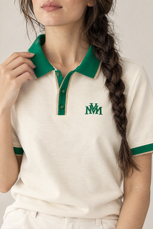 Woman adjusting the green collar of the Club Crest polo, close-up of the green MVM monogram on the chest. Color: Apricot with Green