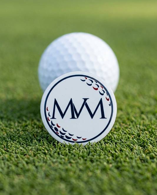 Pure Ball golf ball marker in navy and burgundy print on a putting green next to a golf ball